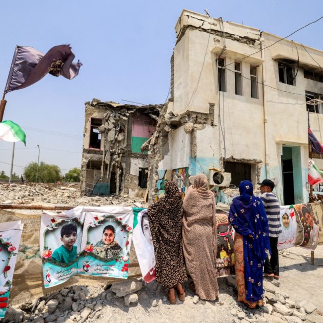 People stand near the building of the destroyed Shajareh Tayyebeh primary school in Minab in Irans Hormozgan province on August 10, 2026. In the early hours of the US and Israel's war with Iran in late February, the school in southern Iran was hit, killing at least 73 boys and 47 girls among more than 150 fatalities, Iranian officials had said. (Photo by ATTA KENARE / AFP) /