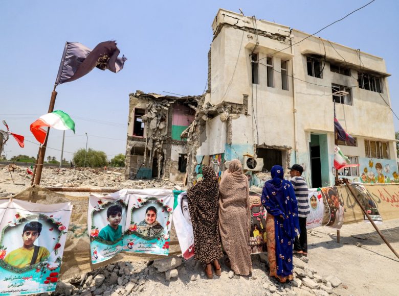People stand near the building of the destroyed Shajareh Tayyebeh primary school in Minab in Irans Hormozgan province on August 10, 2026. In the early hours of the US and Israel's war with Iran in late February, the school in southern Iran was hit, killing at least 73 boys and 47 girls among more than 150 fatalities, Iranian officials had said. (Photo by ATTA KENARE / AFP) /
