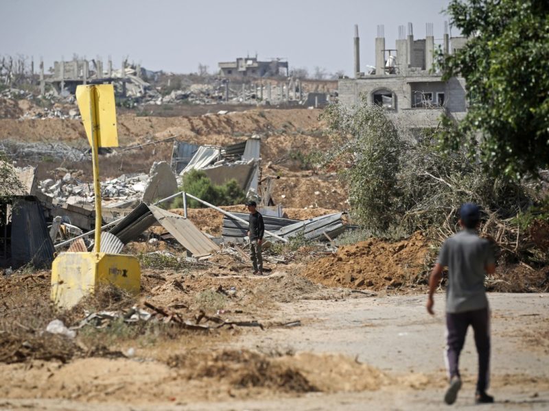 Palestinians walk past a concrete block marking the 'Yellow Line' drawn by the Israeli military in the east of Deir al-Balah, central Gaza Strip on July 22, 2026, as violence has continued in Gaza despite the ceasefire. Gaza remains gripped by daily violence, with both the Israeli military and Hamas accusing one another of violating the truce in effect since October 10. The war flattened swathes of the territory, displaced most of the population at least once, and left hundreds of thousands of people living in tents and temporary shelters. (Photo by Eyad Baba / AFP)